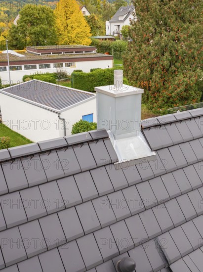 Fireplace with metal cladding on anthracite-colored roof, view over the residential area, house renovation, climate renovation, Metzingen, Germany