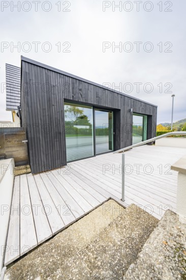 Terrace with wooden deck and glass front, access via ramp with metal handrail, clear modern lines when the sky is overcast, house renovation, air conditioning renovation, Metzingen, Germany