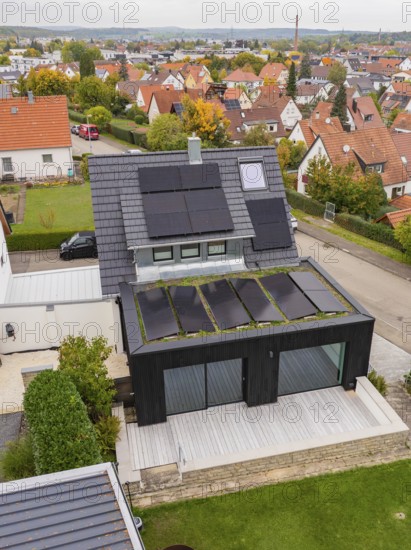 Aerial view of a modern single-family house with solar systems on a gable roof and green extension in a quiet suburban settlement, house renovation, climate renovation, Metzingen, Germany