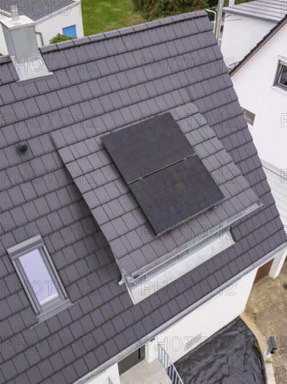 Detail of the roof opening with glass balustrade and two solar modules next to a skylight on a dark-covered gable roof, house renovation, air conditioning renovation, Metzingen, Germany