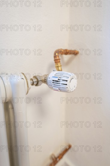 Detail of a radiator thermostat with copper lines on a white wall, house renovation, climate renovation, Metzingen, Germany