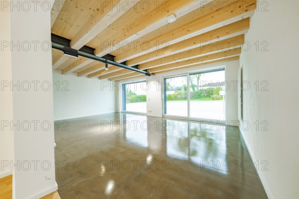 Large, bright living room with exposed wooden beams, polished concrete floor and large sliding doors to the garden, house renovation, air conditioning renovation, Metzingen, Germany