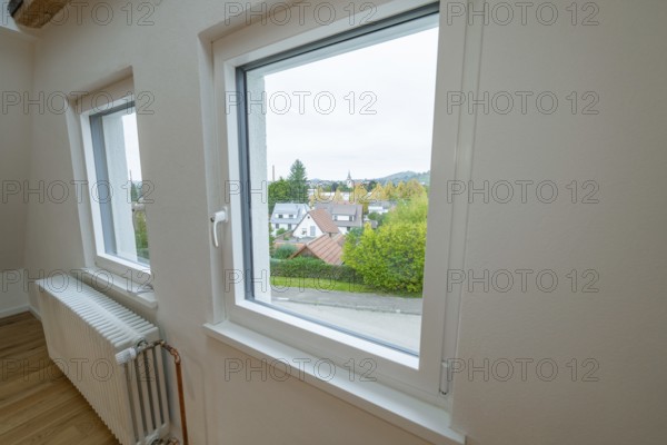 Bright room with white windows and views of residential buildings and greenery, radiator on the window, house renovation, air conditioning renovation, Metzingen, Germany