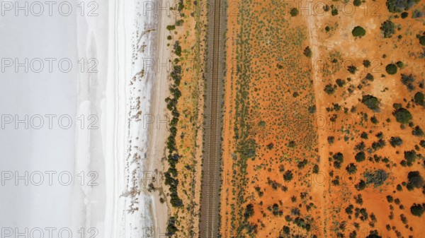 Train tracks divide a saltlake and the desert in the Australian outback, photograped with a drone