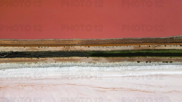 Pink lake next to the xoast, divided by streams and streets, photograped with a drone