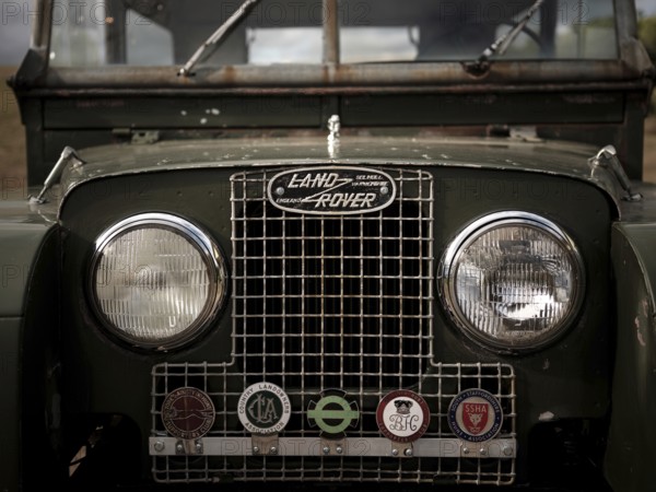 The front end of a 1950's Series One Land Rover, adorned with hunt club badges on the front grill, parked at the Toronto North York Hunt Club in Mulmer, Ontario, Canada