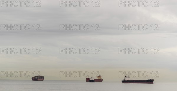 Cargo ships floating on a calm ocean under an overcast sky in Vancouver, British Columbia, Canada