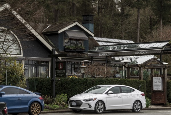 A teahouse in Stanley Park with parked cars, surrounded by lush greenery and overcast skies in Vancouver, British Columbia, Canada