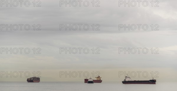 Several ships on the horizon beneath a blanket of clouds in Vancouver, British Columbia, Canada