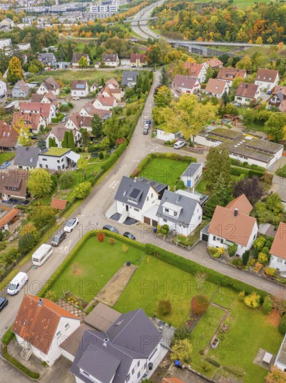 Suburban road with single-family houses and autumn gardens, a motorway in the background, Metzingen, Germany