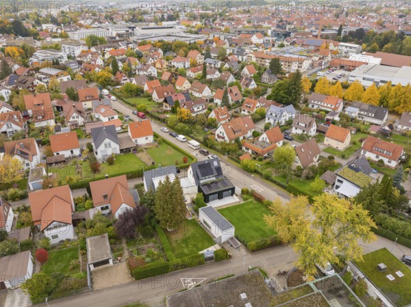 Autumn settlement with yellow tree avenue and view of the city under grey clouds, Metzingen, Germany