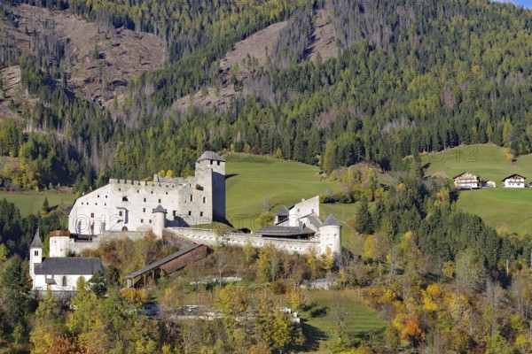 Medieval castle over autumnal forests and meadows in a sunny mountain landscape, Herbstenburg, Drau cycle path, Toblach, Tyrol, Austria
