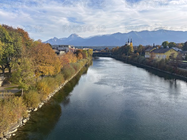 River through a city, autumn trees and mountains in the background under a clear sky, Drau, Drau cycle path, Carinthia, near Villach, Austria