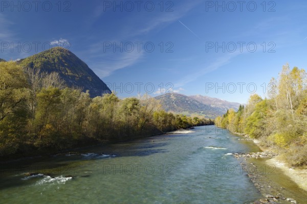 Wide river snakes through an autumnal valley, quiet sky with fine contrails, Lienz, Drau cycle path, Carinthia, Italy