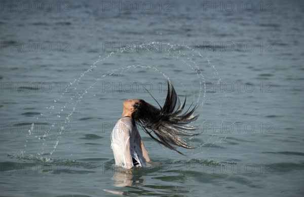 Young cute girl waving hair in the water