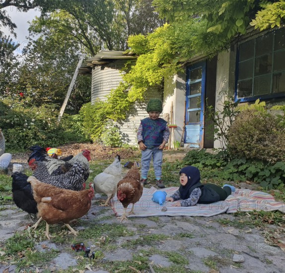 Two small children in the garden on a blanket with chickens, Othenstorf, Mecklenburg-Western Pomerania, Germany