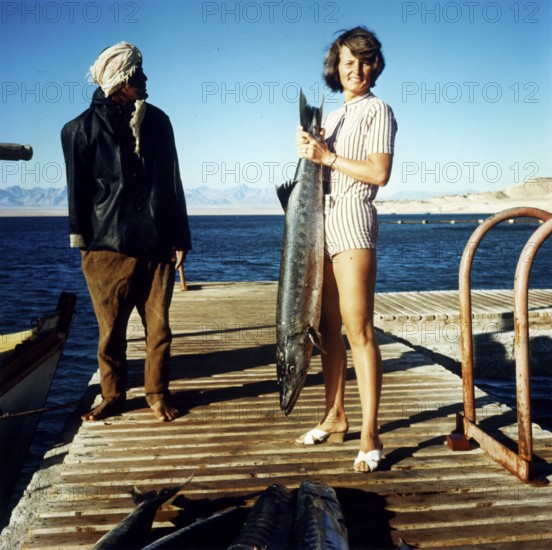 Woman and Egyptian with large captive barracuda, large barracuda (Sphyraena barracuda), about 1, 40 meters long, Red Sea, 1960s, Egypt