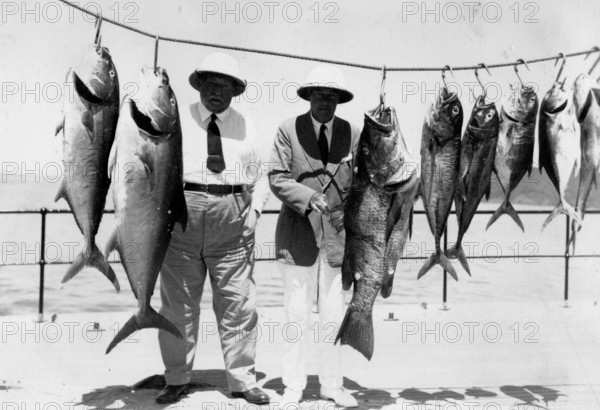 Two men pose with various captured groupers and mackerel, around 1930s, Florida, USA