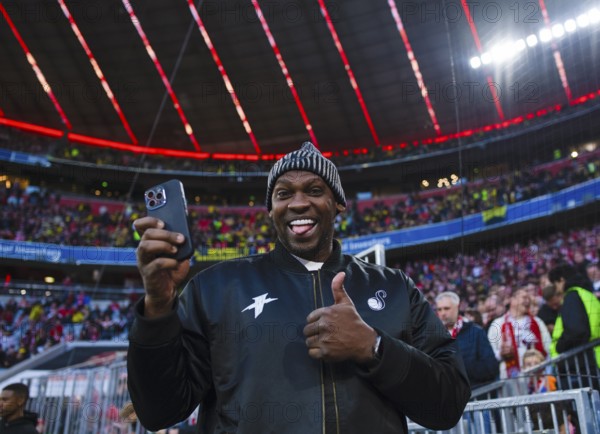 Léo Macaé, former soccer player Brazil, today influencer, gesture gesture thumbs up with smartphone portrait Deutscher Classico, FC Bayern Munich FCB versus Borussia Dortmund BVB, Allianz Arena, Munich, Bayern, Germany