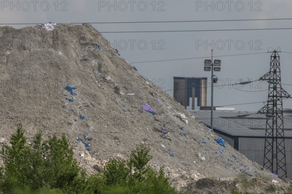 Chimneys, which are not far from factories, rise over mountains of waste. The sky is cloudy and creates a heavily polluted atmosphere. Haut Rhin, Alsace, France