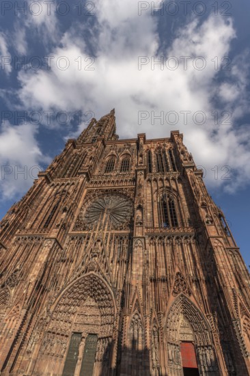 Strasbourg's Notre Dame Cathedral stands majestically there. Its magnificent architectural details are clearly visible under the blue, cloudy sky. Bas Rhin, Alsace, France