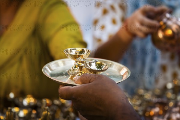People shop for bronze and other metal items at a roadside stall on Dhanteras, in Guwahati, Assam, India on 18 October 2025. On Dhanteras, people traditionally buy precious metals like gold, silver, or even new utensils, as it is believed this brings wealth and good luck into the household