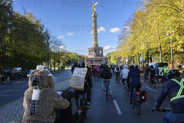 Participants in a bicycle demo against the A100 on the 17th of June road. Signs say: Hitler loves (little heart) Autobahn, CDU continues the delusion #A100, Victory Column, Berlin, 18.10.2025