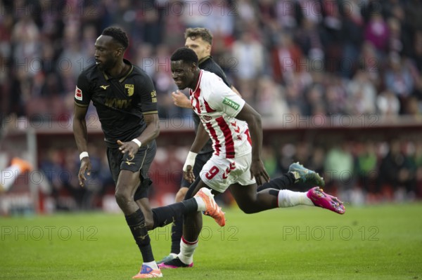 Chrislain Matsima (FC Augsburg, defense, #5), Ragnar Ache (1.FC Cologne, Sturm, #9), COLOGNE, Germany - OCTOBER 18: During the Bundesliga match between FC Cologne vs. FC Augsburg at Rheinenergie-Stadion on matchday 8 of the 1st Bundesliga on October 18, 2025 in Cologne, Germany. DFL REGULATIONS PROHIBIT ANY USE OF PHOTOGRAPHS AS IMAGE SEQUENCES AND/OR QUASI-VIDEO, Rheinenergie-Stadion, Cologne, North Rhine-Westphalia, Germany