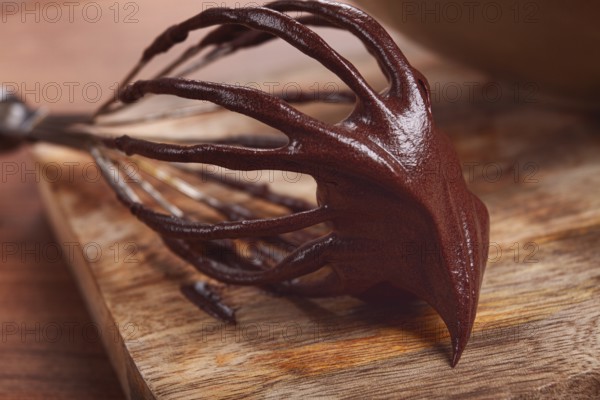 Metal whisk, close-up with chocolate dough, baking, structure and consistency, homemade, top view, no people