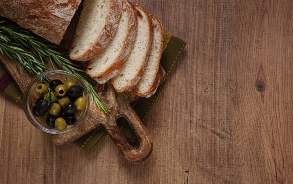 Sliced ciabatta, on a chopping board, with rosemary and olives, Italian bread, close-up, Italian cuisine, breakfast, no people