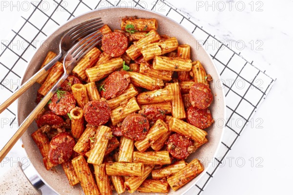Rigatoni pasta with spicy sausage, and rich tomato sauce served, on a white plate, homemade