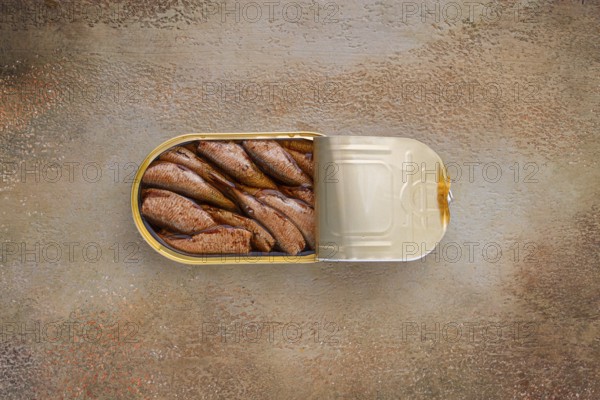 Open tin can with sprats, appetizer, on the table, top view