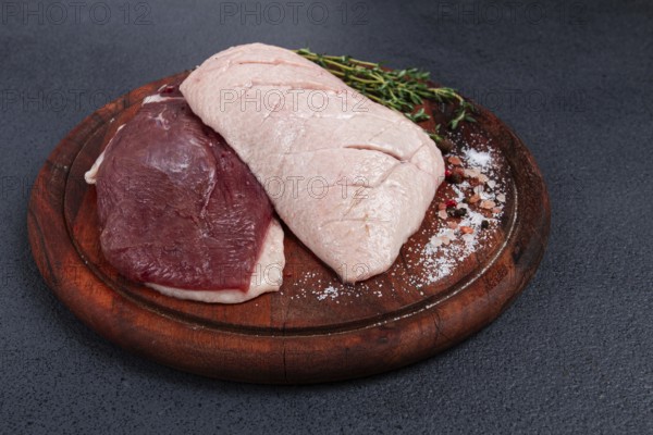 Fresh raw duck breasts, on a wooden chopping board, with herbs and spices, no people