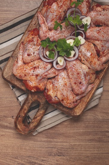 Chicken wings, marinated and laid out on a wooden platter, ready for cooking, grilling or baking, in a home kitchen, there are no people