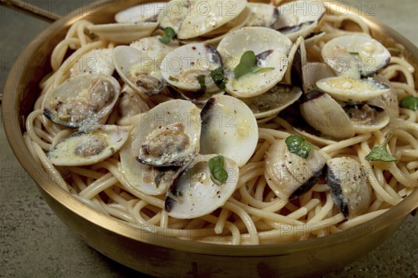 Spaghetti with vongole clams, in cream sauce, carbonara, in a brass pan, homemade, top view, no people