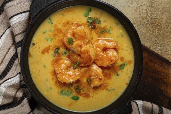Creamy shrimp curry with spices, garnished with herbs, on a textured background, homemade, no people