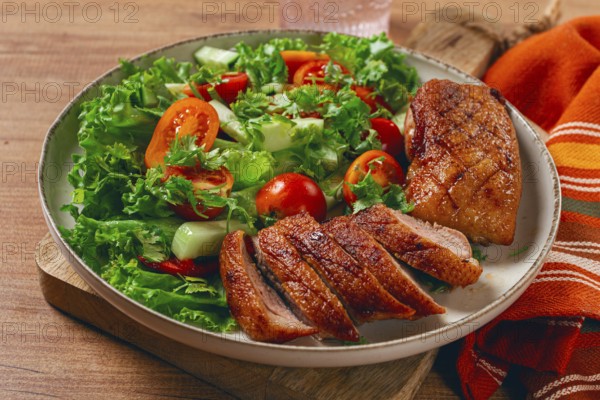 Delicious grilled duck breast served with fresh garden salad and cherry tomatoes at a rustic dining table