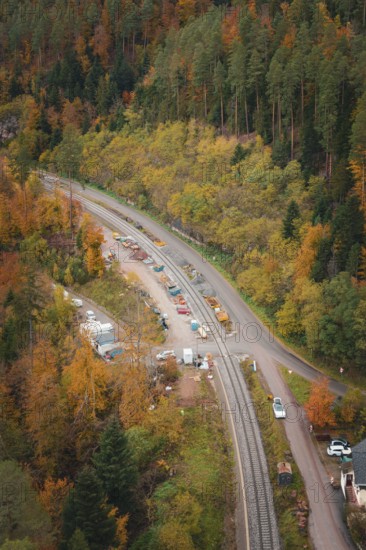 Road and railway line lead through autumn-colored forest, with construction machinery along the route, Hermann-Hesse-Bahn construction site, Calw, Germany