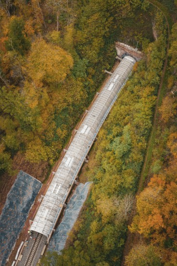 Aerial view of a railway line with tunnel surrounded by autumn trees, Hermann-Hesse-Bahn construction site, Calw, Germany