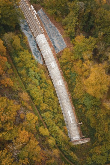 Aerial view of a railway tunnel in a landscape surrounded by autumn trees, Hermann-Hesse-Bahn construction site, Calw, Germany