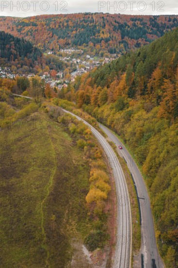 Road and rail along an autumnal hill surrounded by forest, Hermann-Hesse-Bahn construction site, Calw, Germany