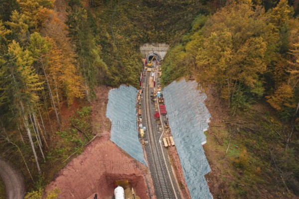 Aerial view of rail construction in autumn forest with tunnel and construction work, Hermann-Hesse-Bahn construction site, Calw, Germany