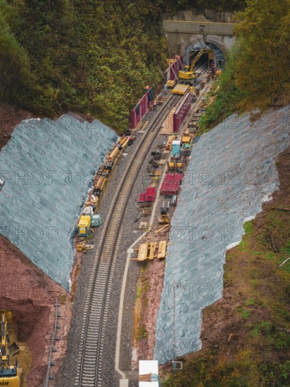 Rails lead into a tunnel surrounded by construction and autumn vegetation, Hermann-Hesse-Bahn construction site, Calw, Germany
