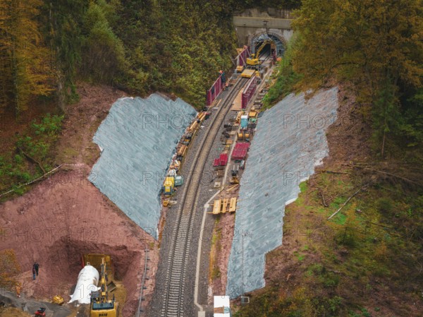 Working at the tunnel entrance to a railway line, with construction equipment and soil in an autumn environment, Hermann-Hesse-Bahn construction site, Calw, Germany
