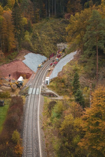 A railway line with construction and tunnel work, surrounded by autumn forests, Hermann-Hesse-Bahn construction site, Calw, Germany