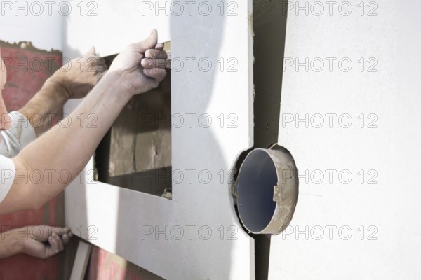Tilers install wall tiles in a new bathroom