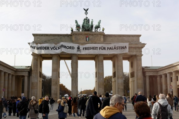 Several activists drop a banner with the inscription Never again genocide, freedom for Palestine and the Palestinian flag and set off pyrotechnics at the Brandenburg Gate, Berlin, 13.11.2025