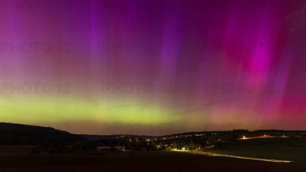 Night sky over a village with aurora borealis. Neckargemünd area, Rhein-Neckar District, Baden-Württemberg, Germany