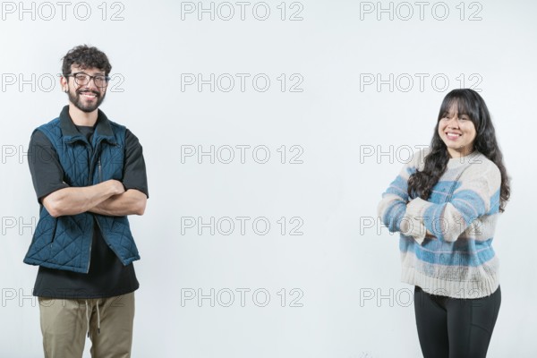 Cheerful young multiethnic couple with arms crossed, isolated. Smiling young couple with crossed arms looking at camera, isolated