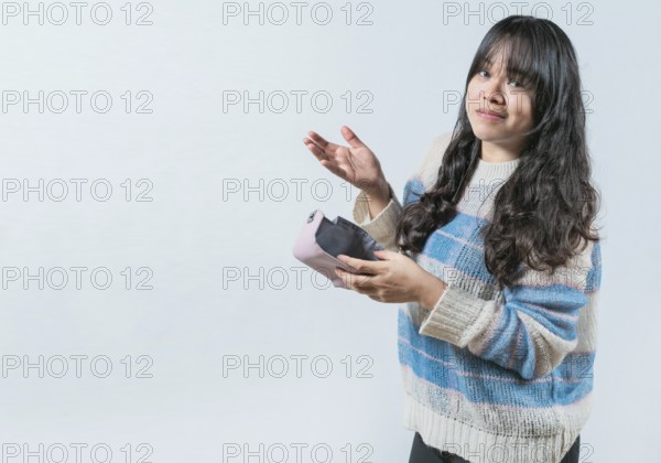 Worried person showing empty wallet isolated. Portrait of bankrupt Asian woman showing empty wallet